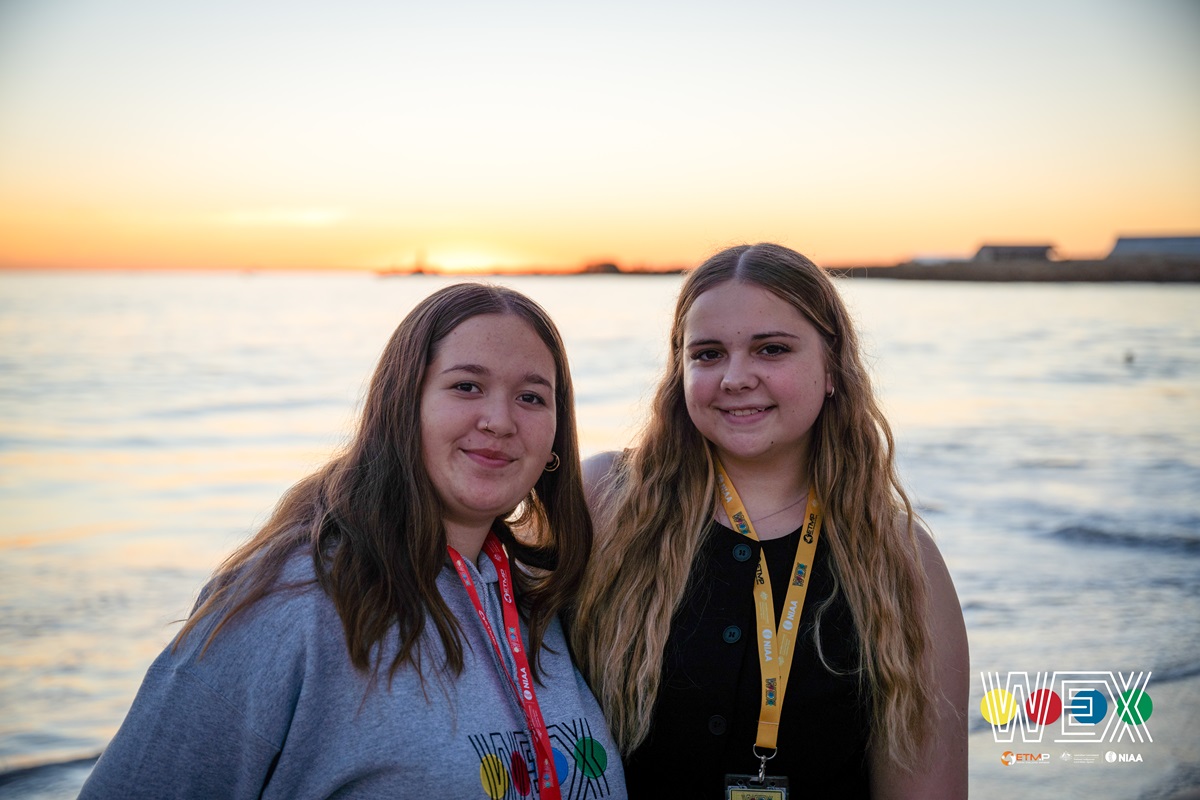 Two girls smile in front of a sun set