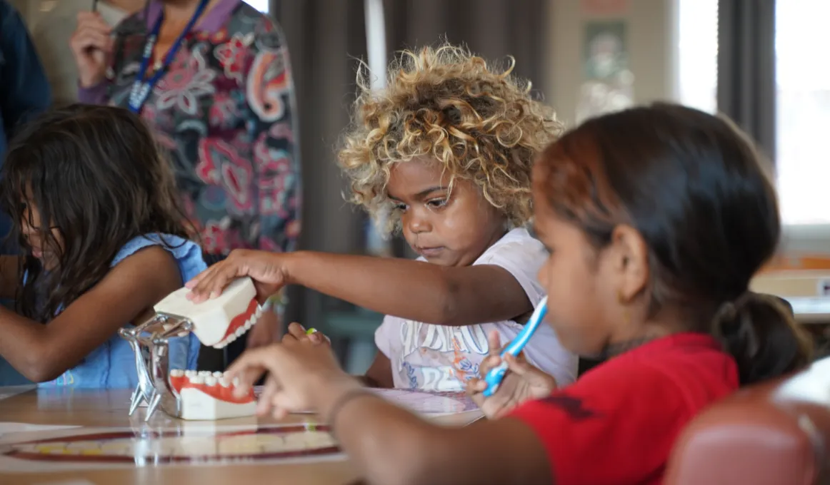 Two children learn from a model jaw and teeth