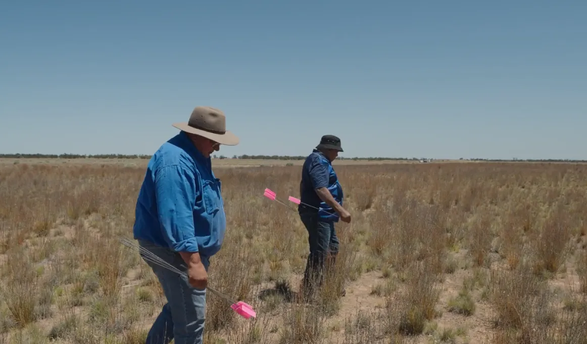 Two men walk across a dry lake bed