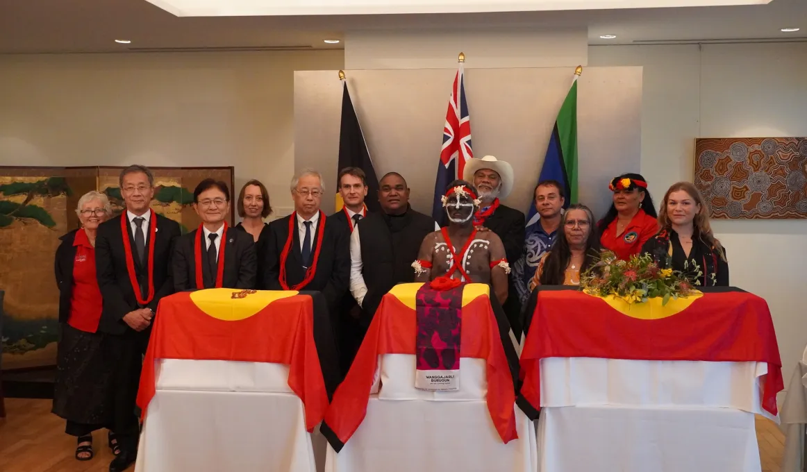 Members stand together behind 3 tables with special containers