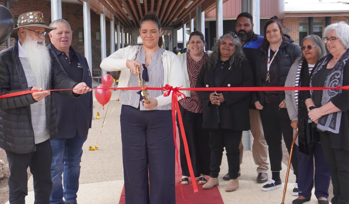 A lady cuts the ribbon to open a new building