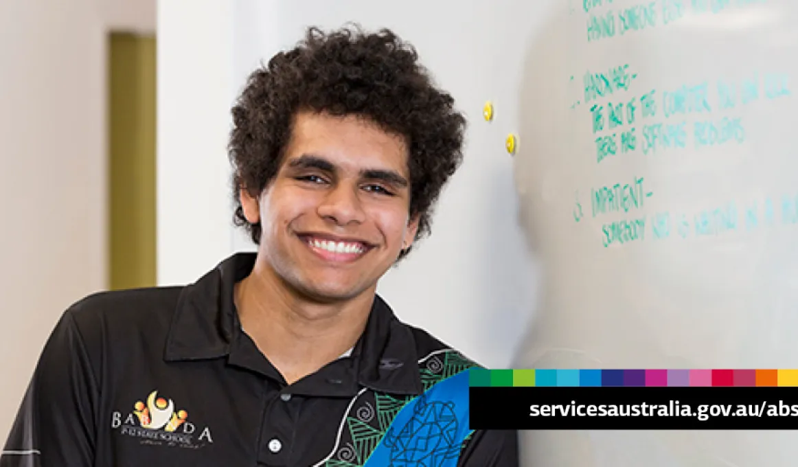 Young adult male leans against a wall. Words to his left say servicesaustralia.gov.au/abstudy