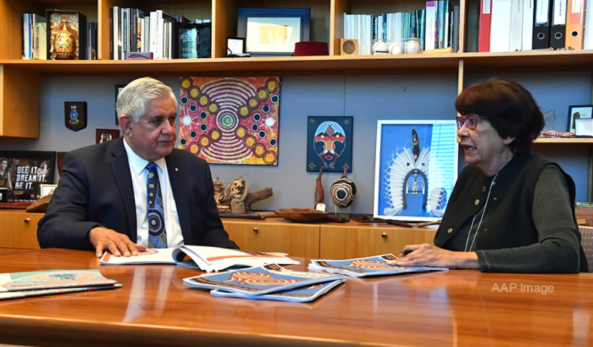 Joint Council on Closing the Gap Co-chairs Minister for Indigenous Australians, the Hon Ken Wyatt AM, MP and Pat Turner AM sitting at a meeting table with papers on the table. In the background is a bookshelf with Indigenous artwork and books.