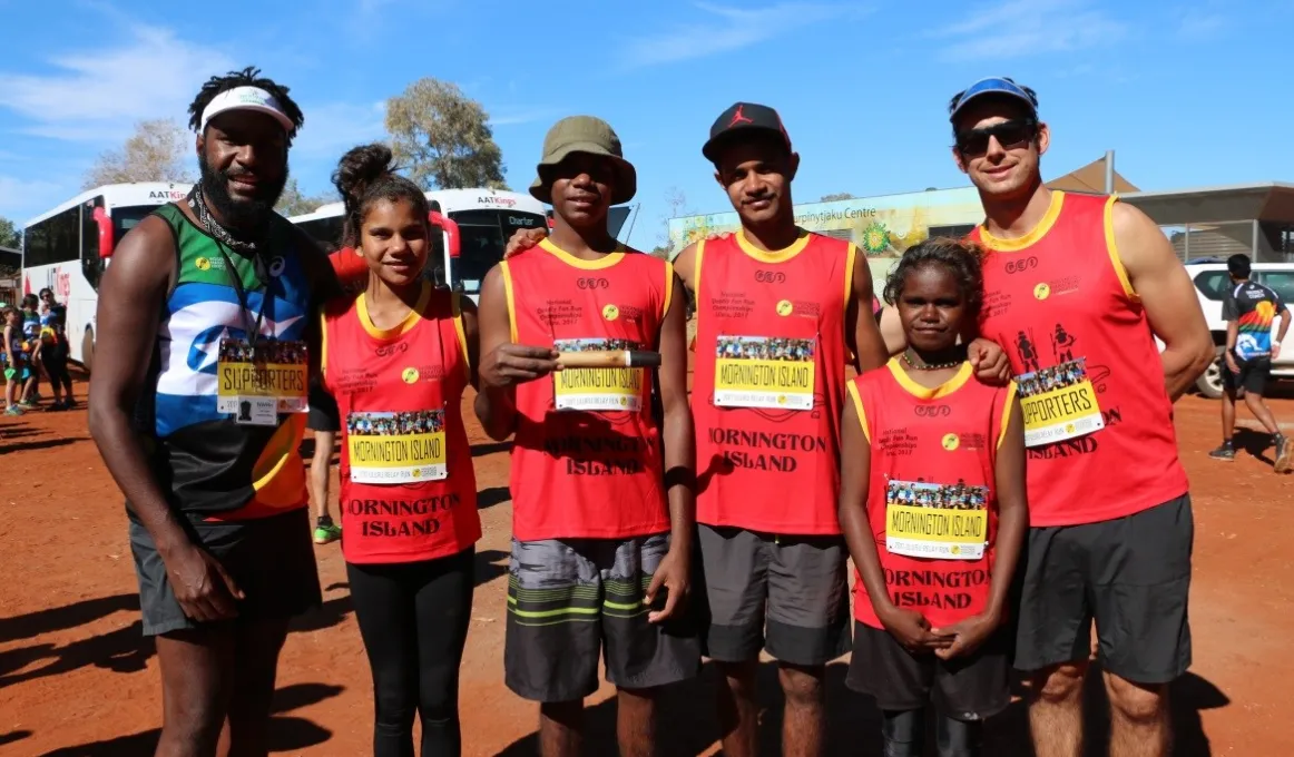 Six young athletes stand in the red dirt of central Australia.