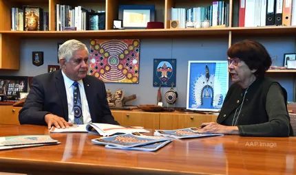 Joint Council on Closing the Gap Co-chairs Minister for Indigenous Australians, the Hon Ken Wyatt AM, MP and Pat Turner AM sitting at a meeting table with papers on the table. In the background is a bookshelf with Indigenous artwork and books.