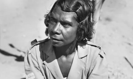 Indigenous woman with hair pinned back wearing army style clothing.