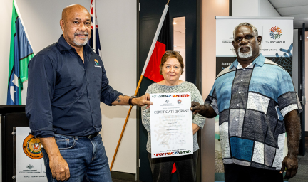 Two men hold a Certificate up in front of a woman in an office
