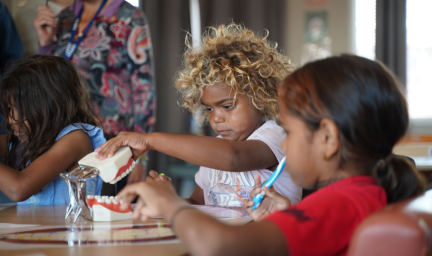 Two children learn from a model jaw and teeth