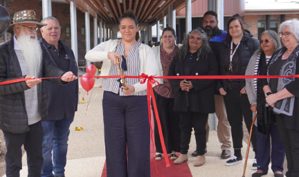 A lady cuts the ribbon to open a new building