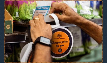 Hands putting a Cheaper prices for you wobbly sign on a store shelf