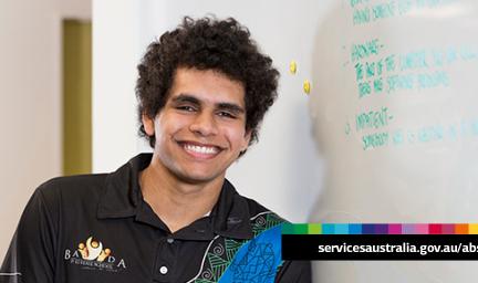Young adult male leans against a wall. Words to his left say servicesaustralia.gov.au/abstudy