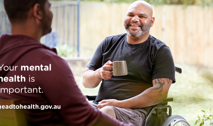 Two men sit opposite each other, oine in a wheel chair and holding a mug. He wears a dark t-shirt the other a maroon hoodie. Overlaid are the words: your mental health is important. headtohealth.gov.au. In the background is a pale coloured fence.